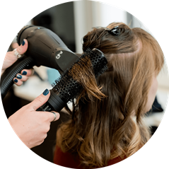hair stylist blow drying hair with blow dryer and brush