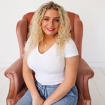 women smiles and sits on red chair 